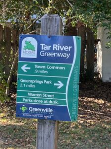 Signage in a post at the Tar River Greenway showing the mileage to points of interest.